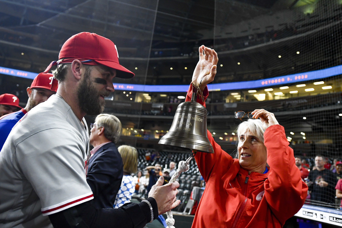 Bryce Harper rings the Phillies’ liberty bell, held by Sheree McMullen, after beating the Padres in NLCS Game 5 to clinch the NL pennant and a trip to the World Series.