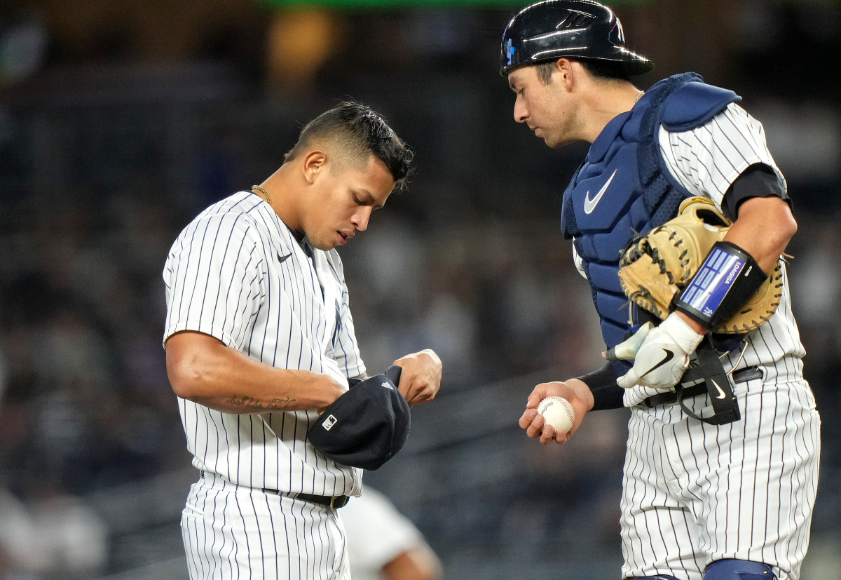 Yankees righthander Jonathan Loáisiga adjusts his PitchCom device with the help of catcher Kyle Higashioka.