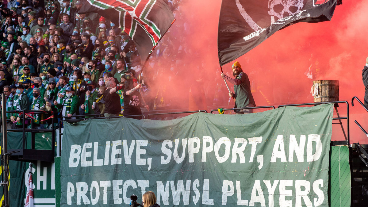 Portland Thorns fans hold up a banner that says, “Believe, support, and protect NWSL players.”