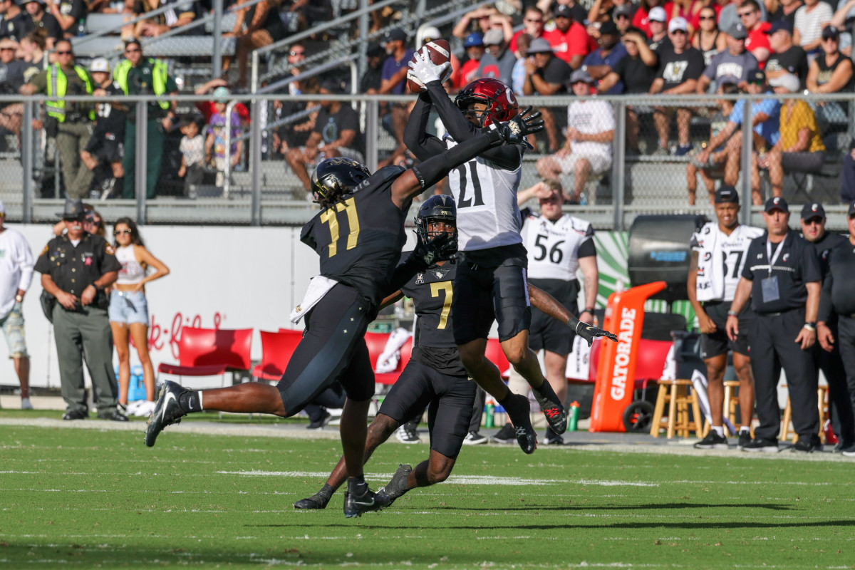 Oct 29, 2022; Orlando, Florida, USA; Cincinnati Bearcats wide receiver Tyler Scott (21) catches a pass as UCF Knights linebacker Jeremiah Jean-Baptiste (11) and cornerback Davonte Brown (7) move in during the second quarter at FBC Mortgage Stadium. Mandatory Credit: Mike Watters-USA TODAY Sports