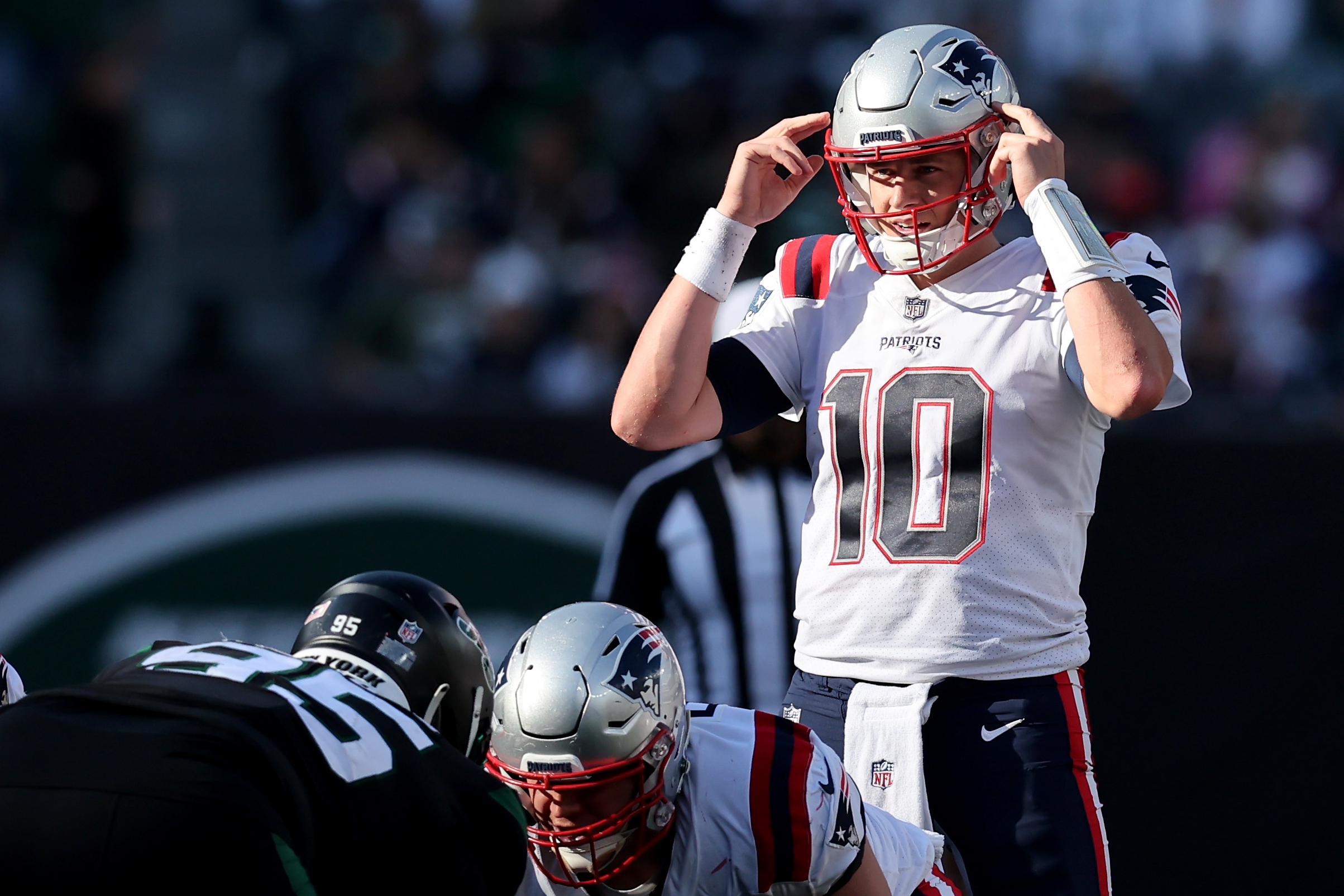 Patriots quarterback Mac Jones signals by pointing to his helmet