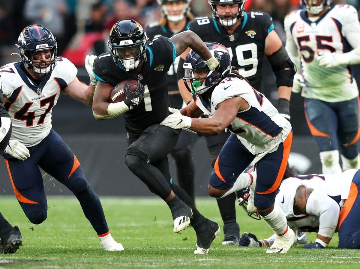 Jacksonville Jaguars running back Travis Etienne Jr. (1) breaks a tackle from Denver Broncos linebacker Nik Bonitto (42) in the fourth quarter during an NFL International Series game at Wembley Stadium.