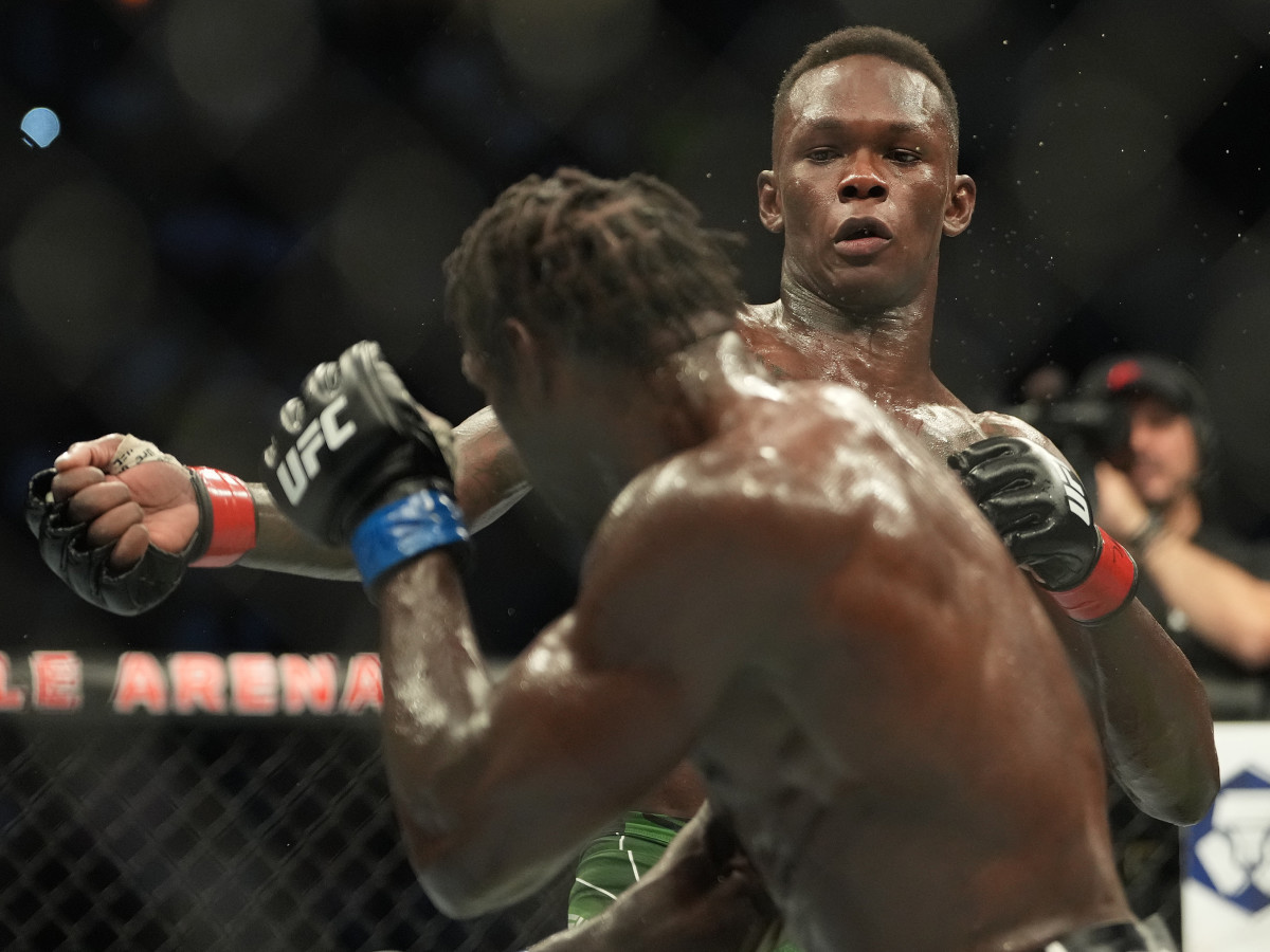 Israel Adesanya (red gloves) and Jared Cannonier (blue gloves) fight in a bout during UFC 276 at T-Mobile Arena.