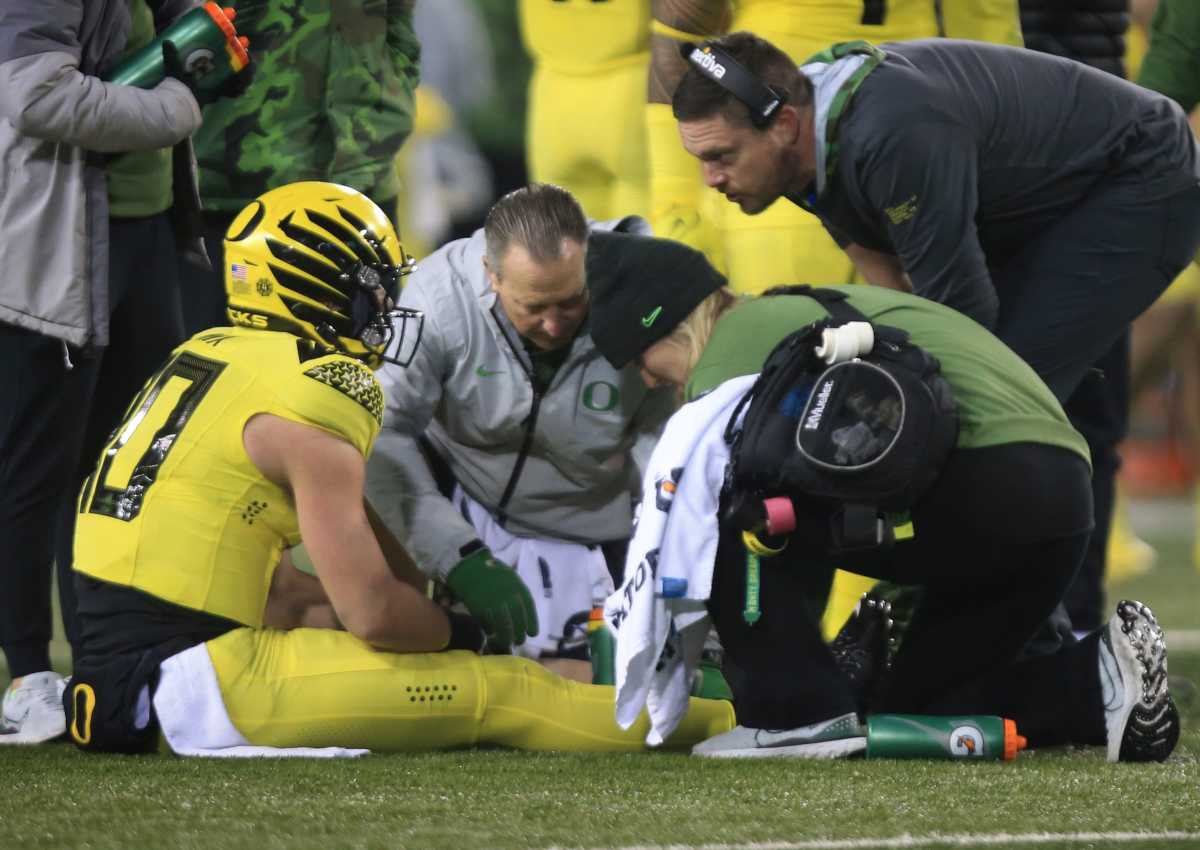 Oregon quarterback Bo Nix, left, sits in the turf after being injured on a fourth quarter play against Washington, Saturday, Nov. 12, 2022, at Autzen Stadium in Eugene, Ore.