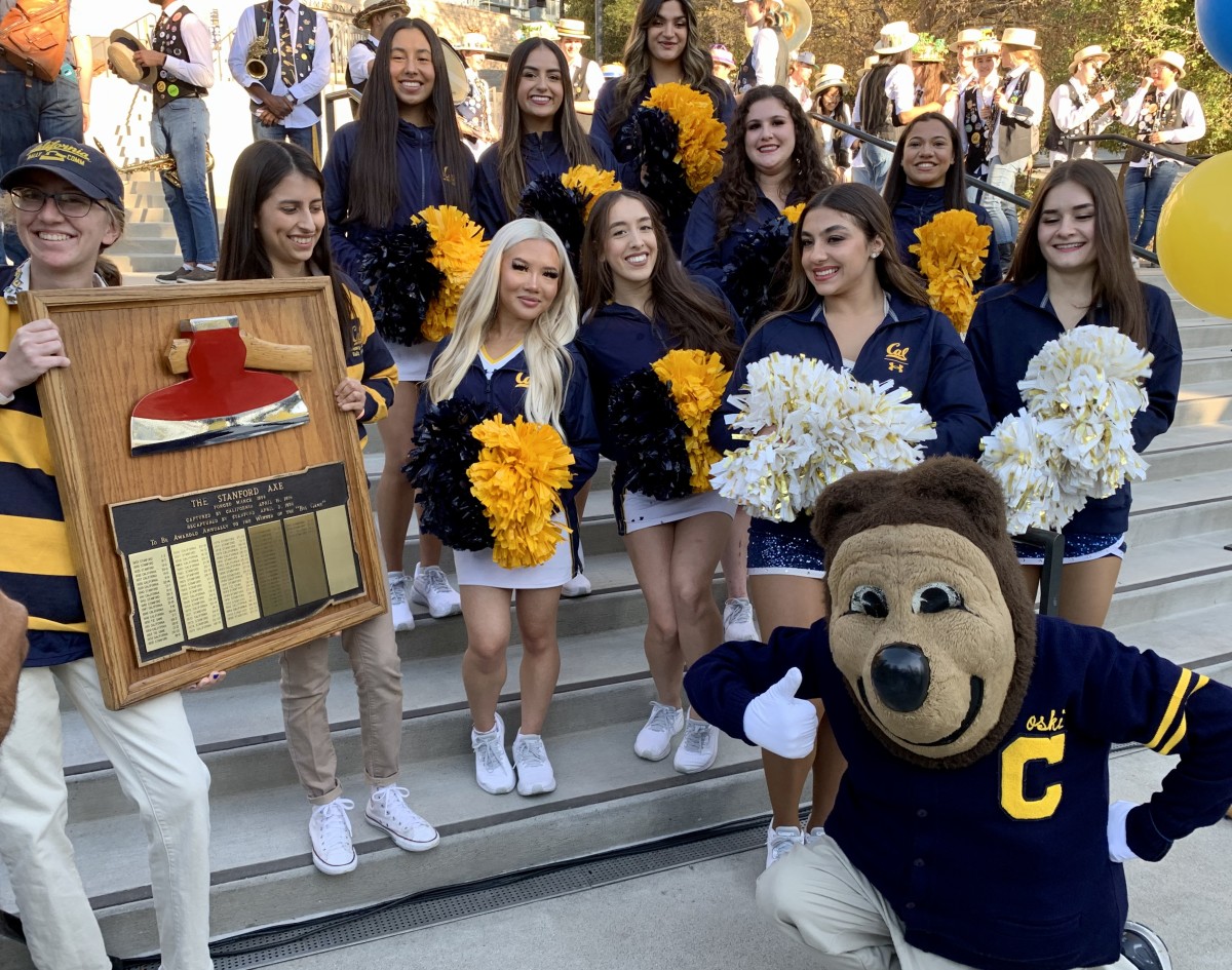 Cal mascot Oski poses with cheerleaders and the Stanford Axe.
