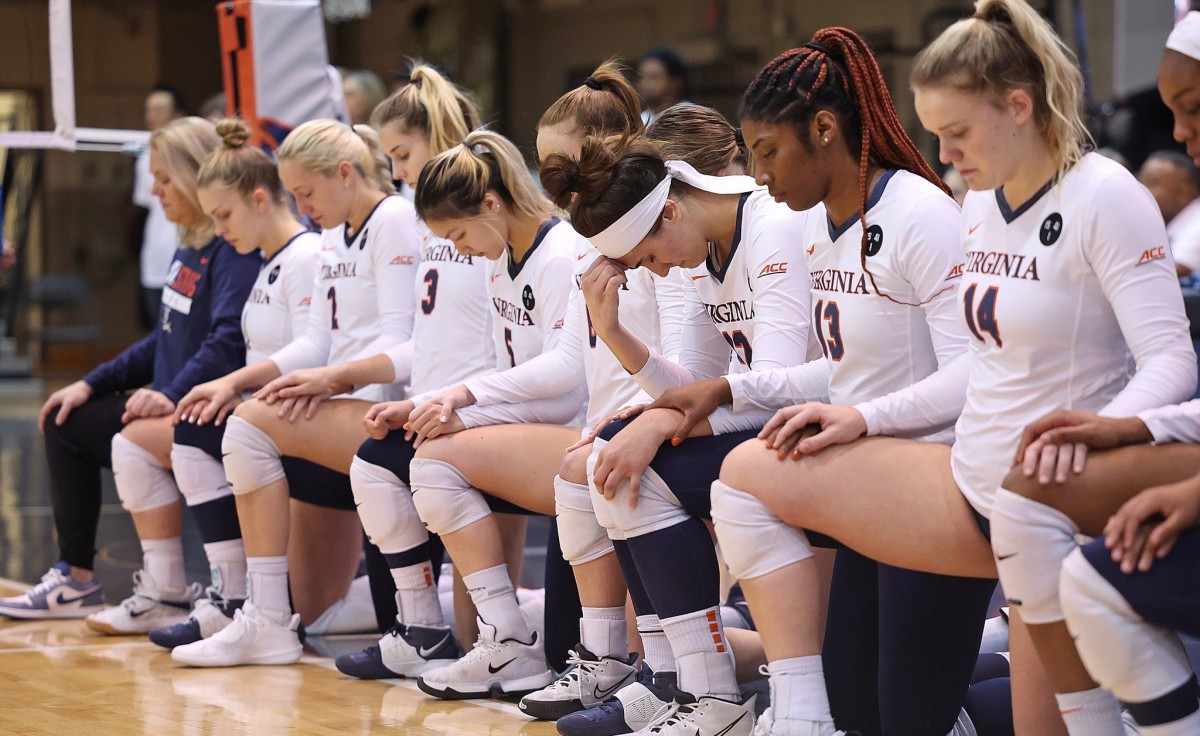 The Virginia volleyball team kneels during a moment of silence before the match against Wake Forest at Memorial Gymnasium.