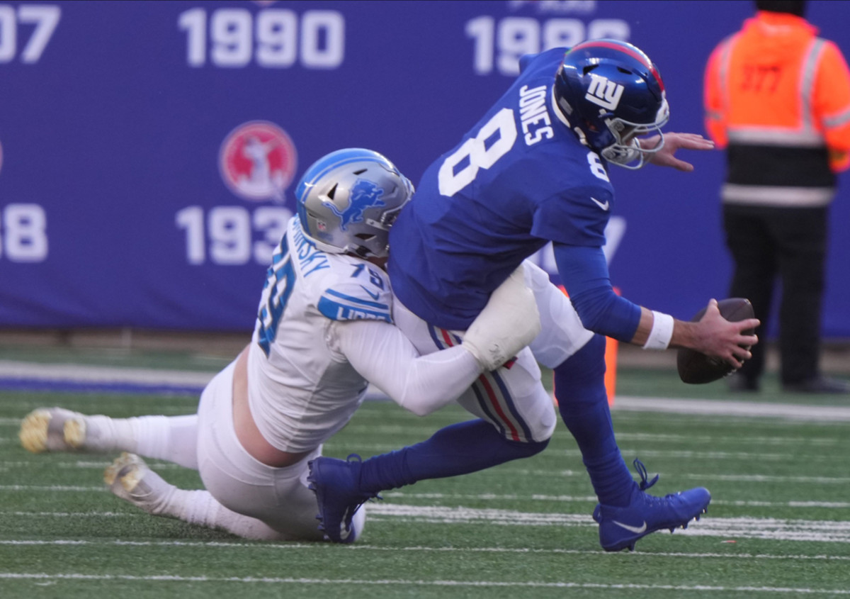 Detroit Lions defensive lineman John Cominsky tackles New York Giants quarterback Daniel Jones.