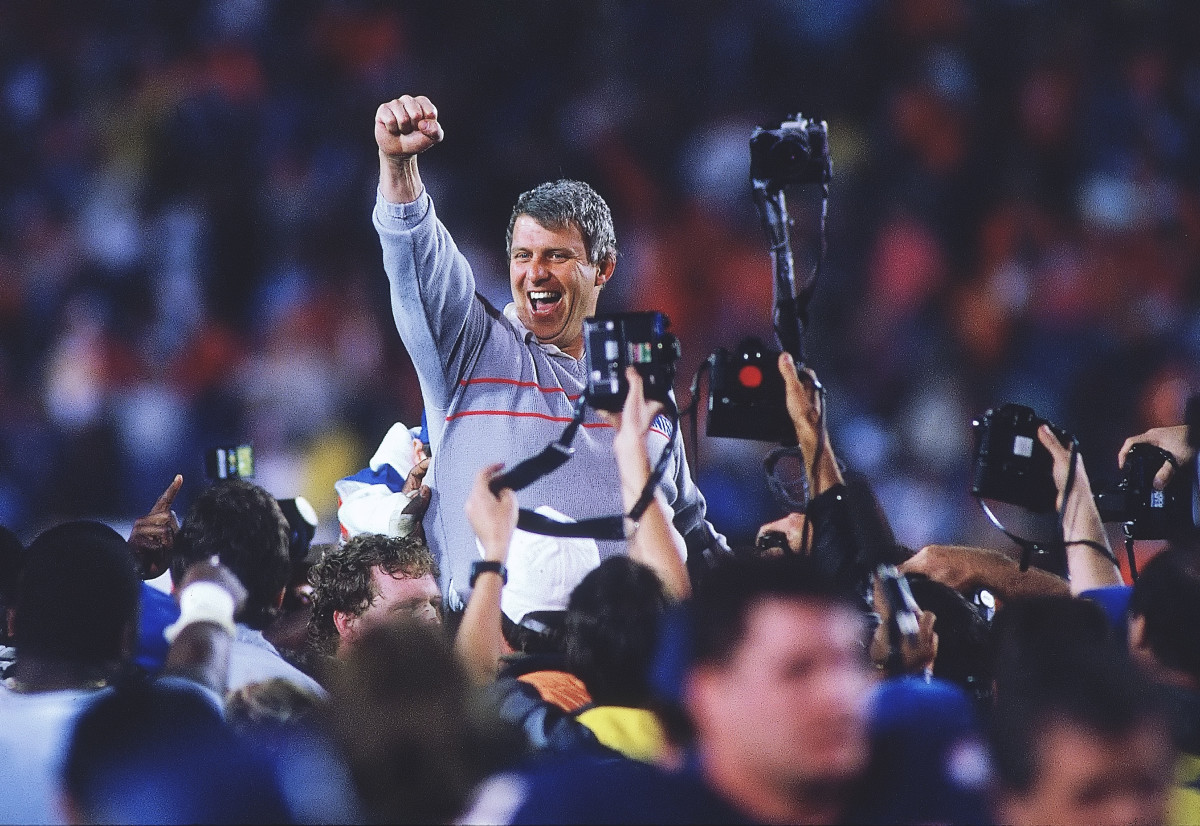 Bill Parcells pumps his fist in the air as he is lifted above the crowd
