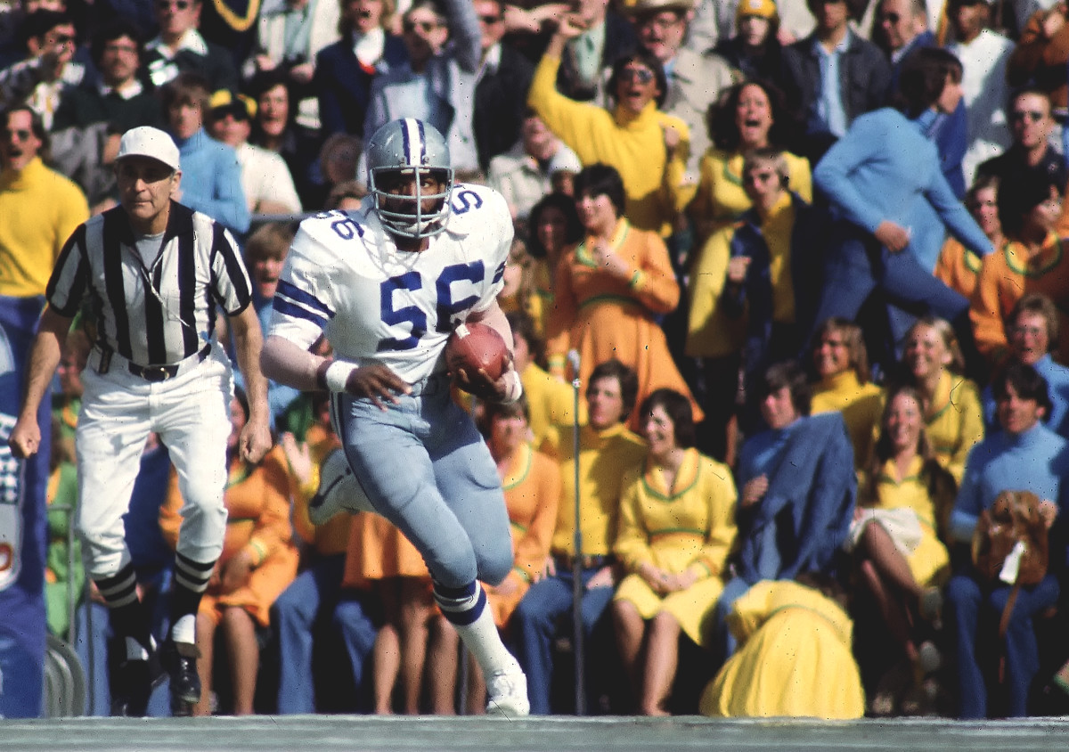 Thomas Henderson runs with the ball as fans dressed in yellow clothes sit in the stands behind him