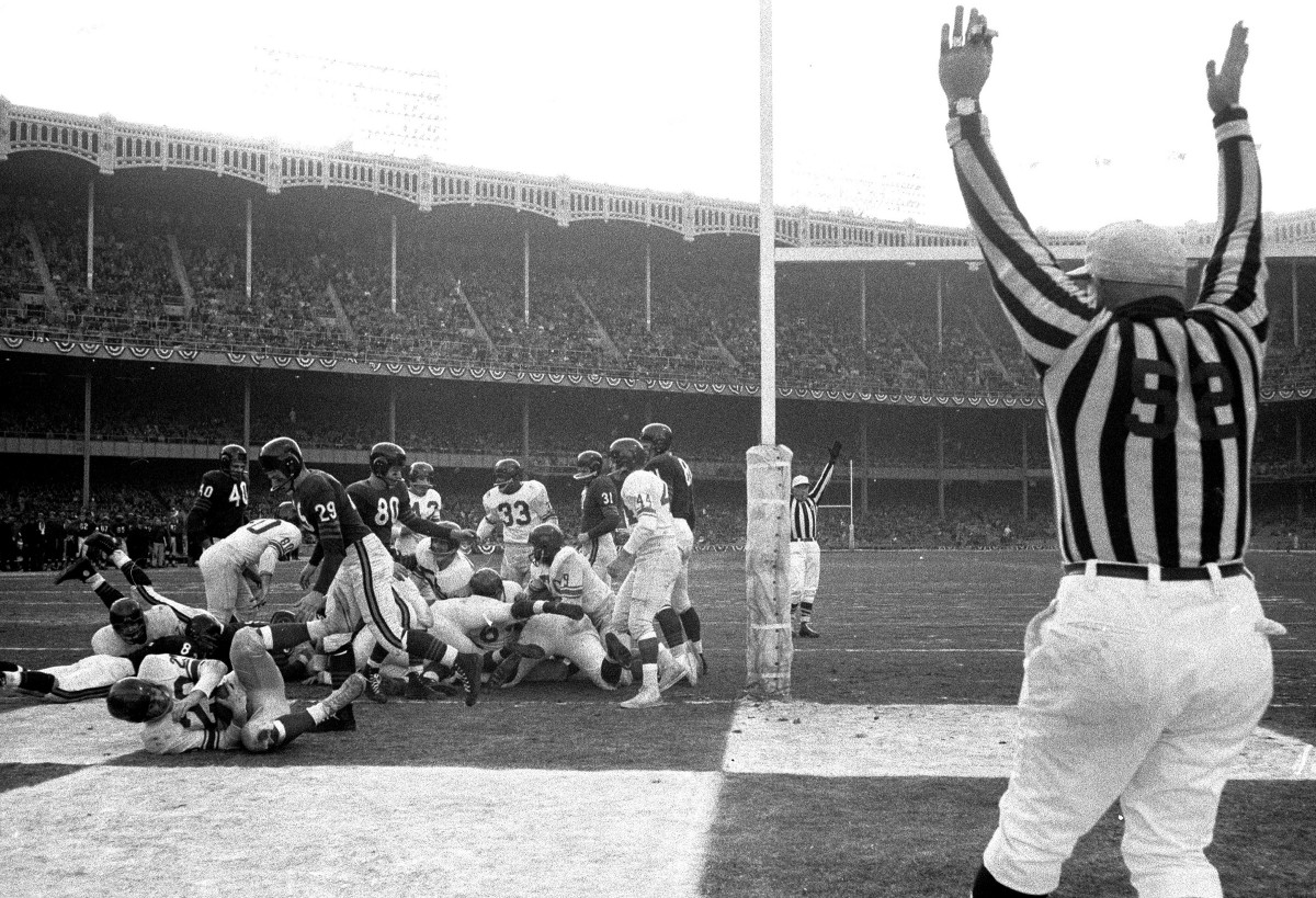 Alex Webster scores in a dogpile of people as a ref stands with his arms up in the endzone