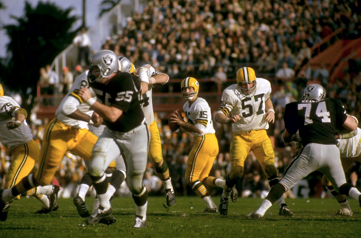 Bart Starr drops back to throw the football as Raiders players try to rush him