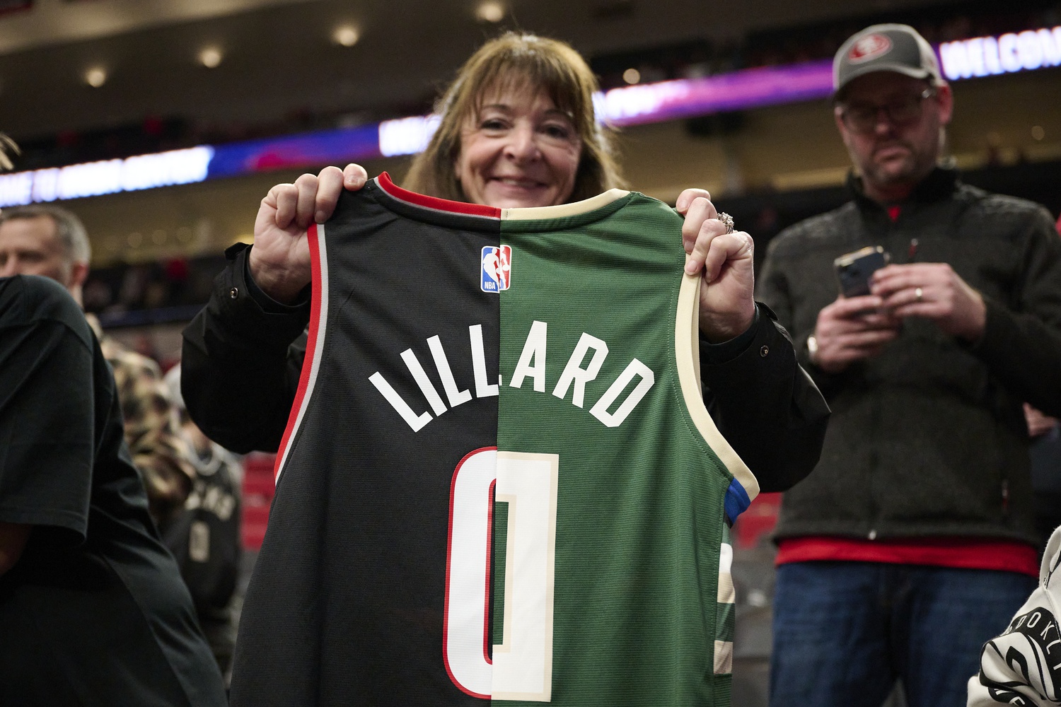 A basketball fan holds a jersey with the colors and number of the Portland Trail Blazers and Milwaukee Bucks guard Damian Lillard (0) a