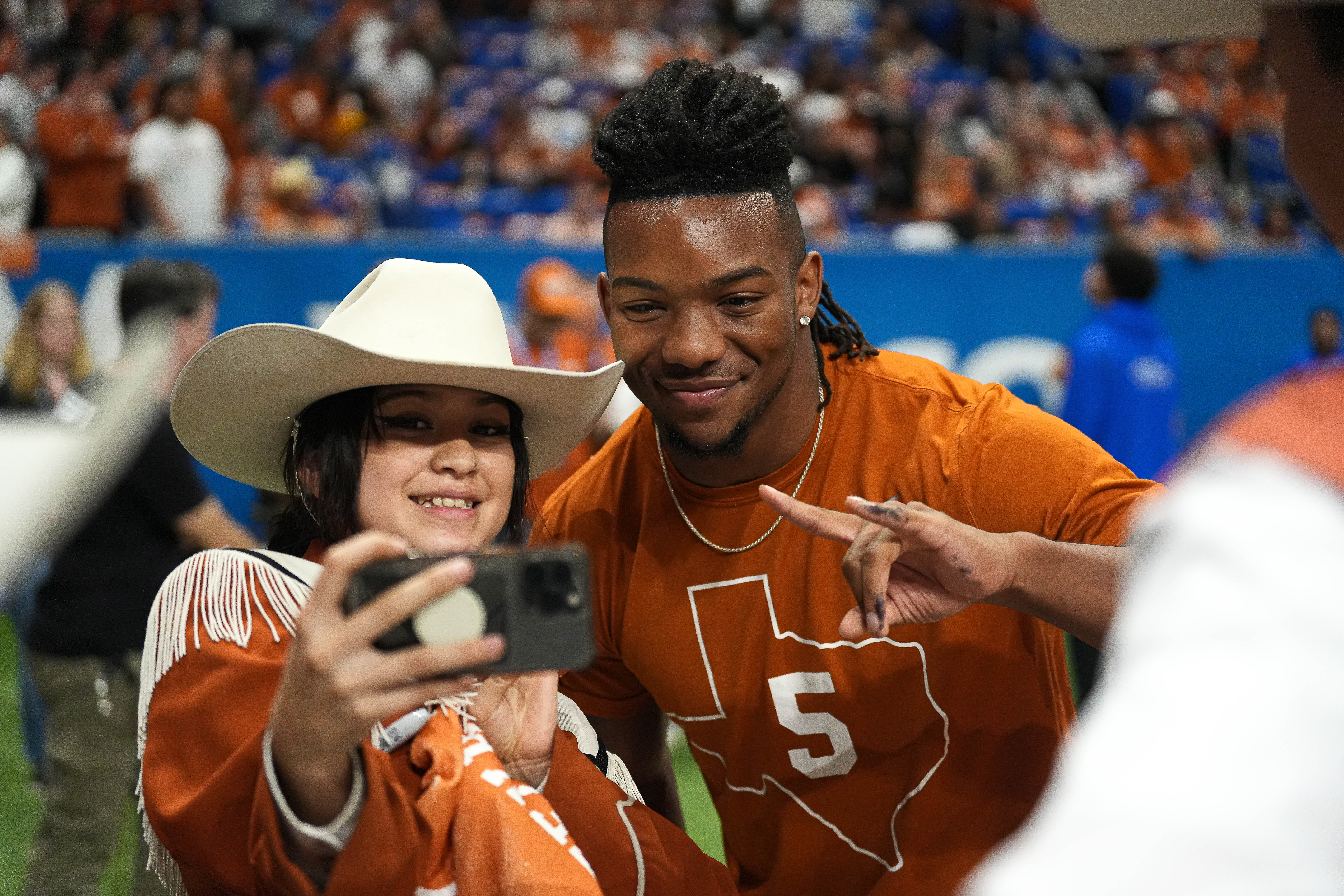 Texas Longhorns running back Bijan Robinson takes a photo with a band member before the Alamo Bowl at the Alamodome, Dec. 29, 2022 in San Antonio.