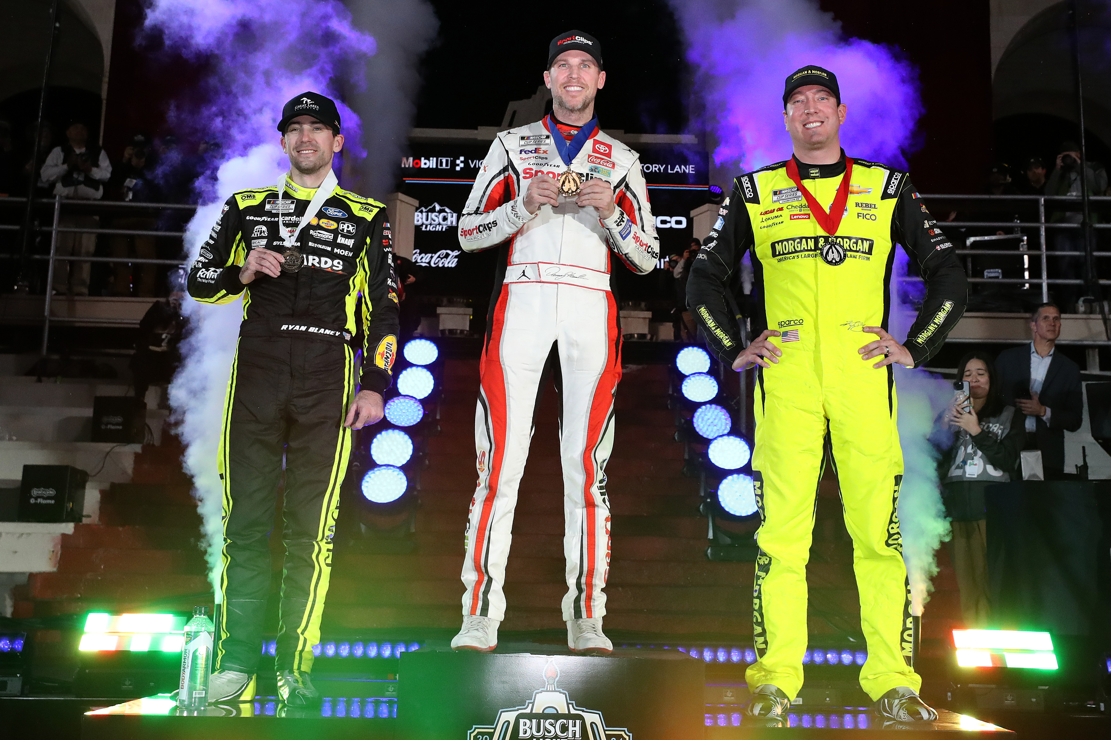 2024 Busch Clash winner Denny Hamlin (middle), second-place finisher Kyle Busch (right), and third-place finisher Ryan Blaney (left), pose on the podium in victory lane at the Los Angeles Memorial Coliseum on Saturday night. (Photo by Meg Oliphant/Getty Images)