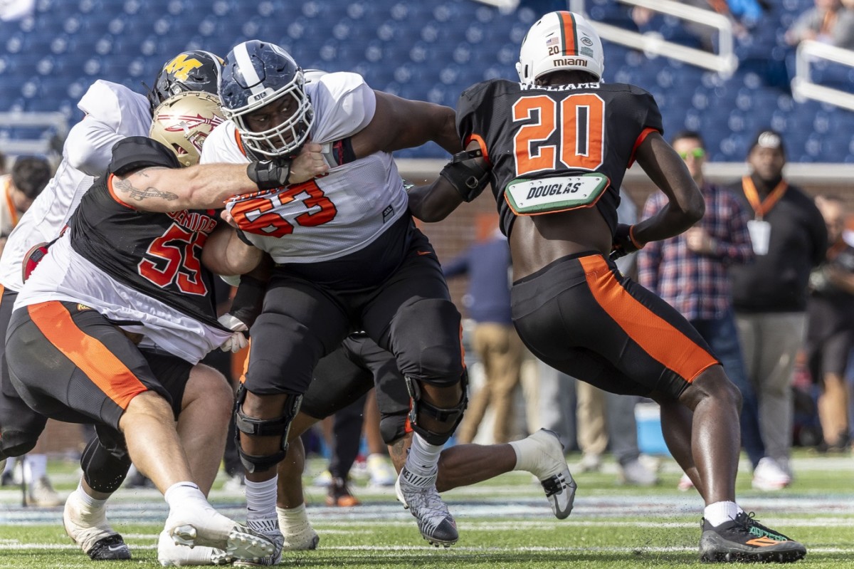 Feb 1, 2024; Mobile, AL, USA; American offensive lineman Christian Haynes of UConn (63) battles with American defensive lineman Braden Fiske of Florida State (55) and American linebacker James Williams of Miami (20) during practice for the American team at Hancock Whitney Stadium. Mandatory Credit: Vasha Hunt-USA TODAY Sports  