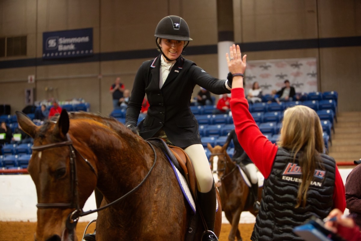 Delaware State assistant coach Caroline Kane high-fives one of her student-athletes during a competition. Kane is one of 25 former NCEA athletes who have returned to serve as a coach for the Division I program after completing their respective careers.