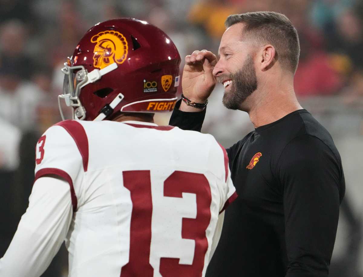 The former Arizona Cardinals head coach and now USC Trojans assistant coach Kliff Kingsbury talks to quarterback Caleb Williams (13) during the pregame warmup before playing the Arizona State Sun Devils at Mountain America Stadium in Tempe on Sept. 23, 2023.