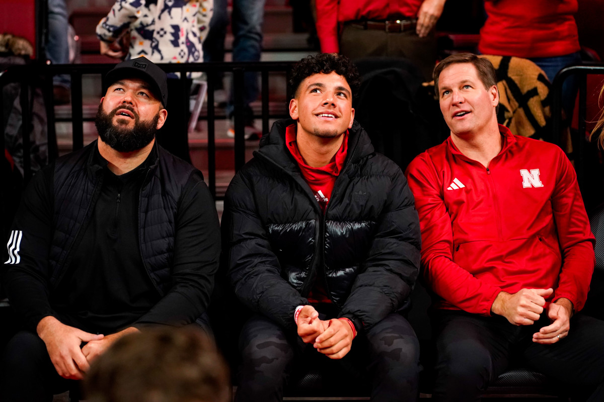 Jan 3, 2024; Lincoln, Nebraska, USA; Nebraska football assistant coach Donovan Raiola (left), his nephew Dylan Raiola (center) and athletic director Trev Alberts sit courtside before the men's basketball game against the Indiana Hoosiers at Pinnacle Bank Arena.
