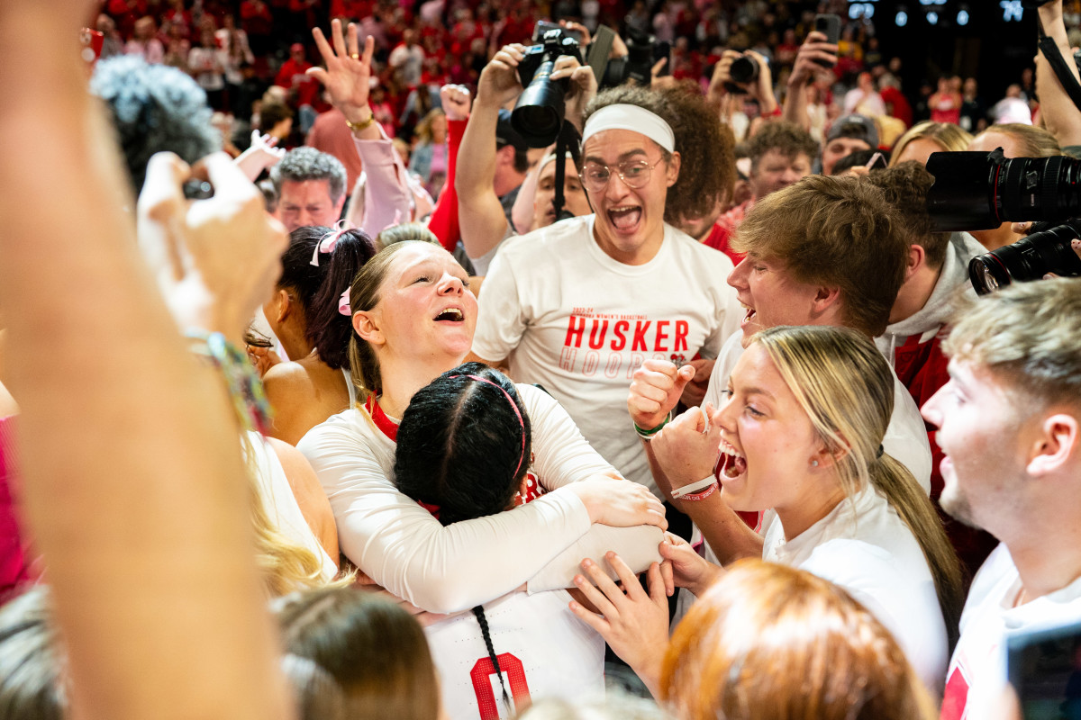 Feb 11, 2024; Lincoln, Nebraska, USA; The Nebraska Cornhuskers celebrate as fans storm the court after defeating the Iowa Hawkeyes at Pinnacle Bank Arena.