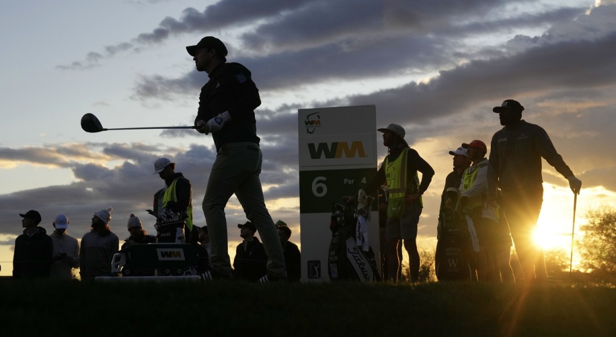 Nick Taylor tees off as the sun begins to go down in Phoenix.