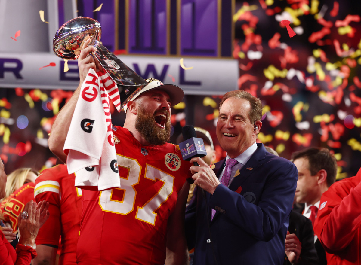 travis kelce holds up the lombardi trophy screaming into a microphone