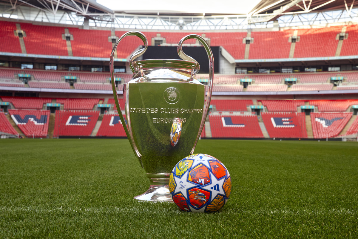 A photo showing the UEFA Champions League trophy on the pitch at Wembley Stadium alongside the official match ball that will be used throughout the knockout phase in the 2023/24 season