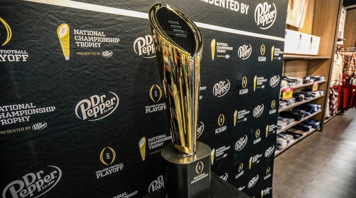The college football National Championship Trophy sits in front of a banner before a game.