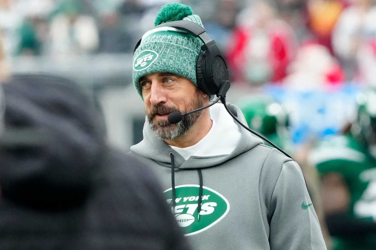 Aaron Rodgers stands on the sidelines for the jets wearing a headset.