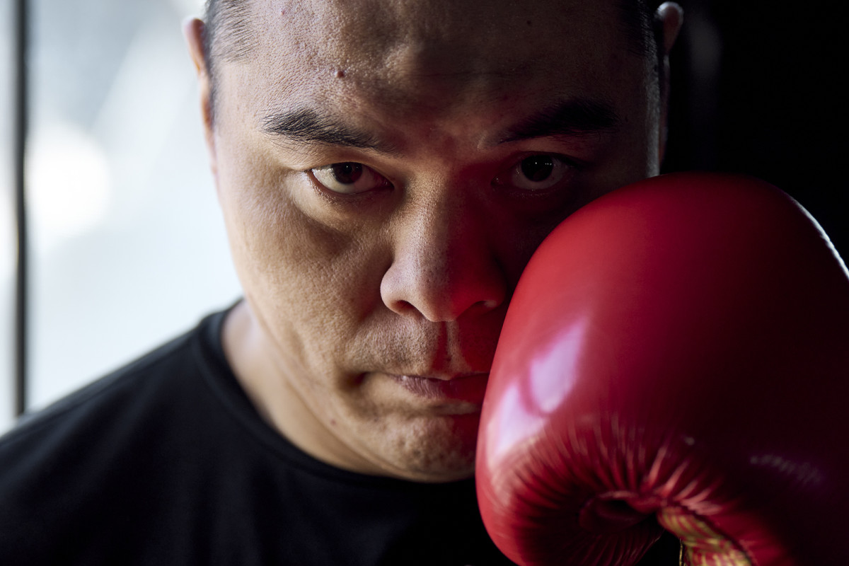 A close up of boxer Zhilei Zhang holding up a red glove near his face.