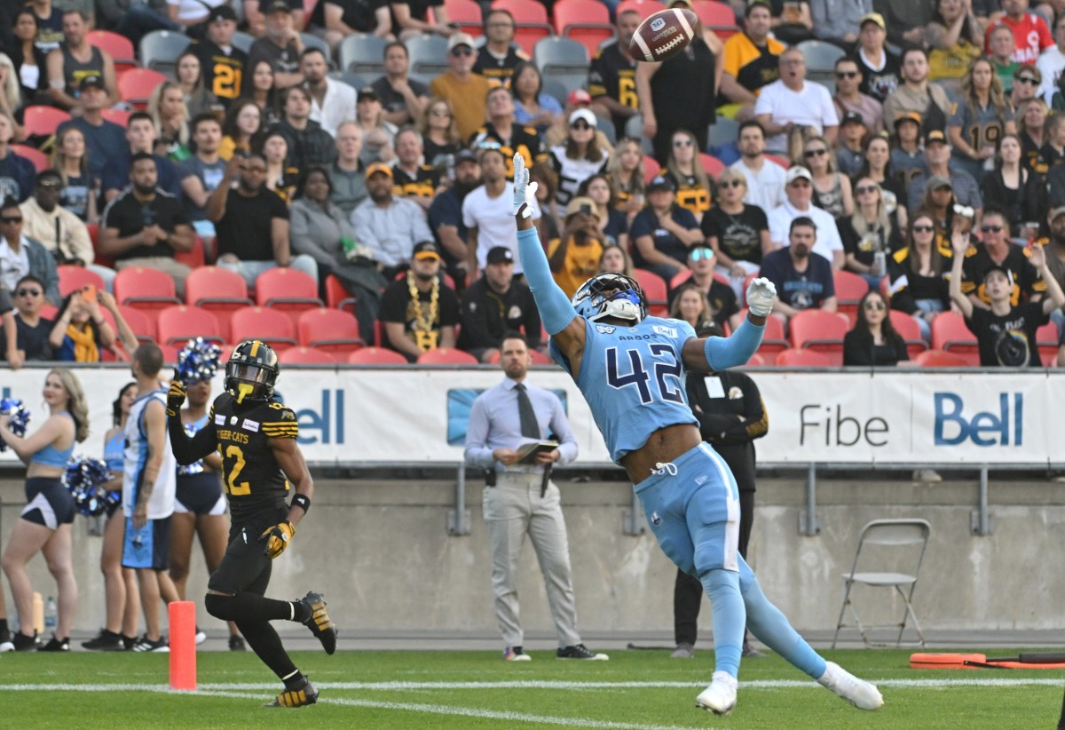 Jun 18, 2023; Toronto, Ontario, CAN; Toronto Argonauts defensive back Qwan'tez Stiggers (42) reaches up to intercept a pass intended for Hamilton Tiger-Cats wide receiver Tim White (12) in the first quarter at BMO Field. Mandatory Credit: Dan Hamilton-USA TODAY Sports  