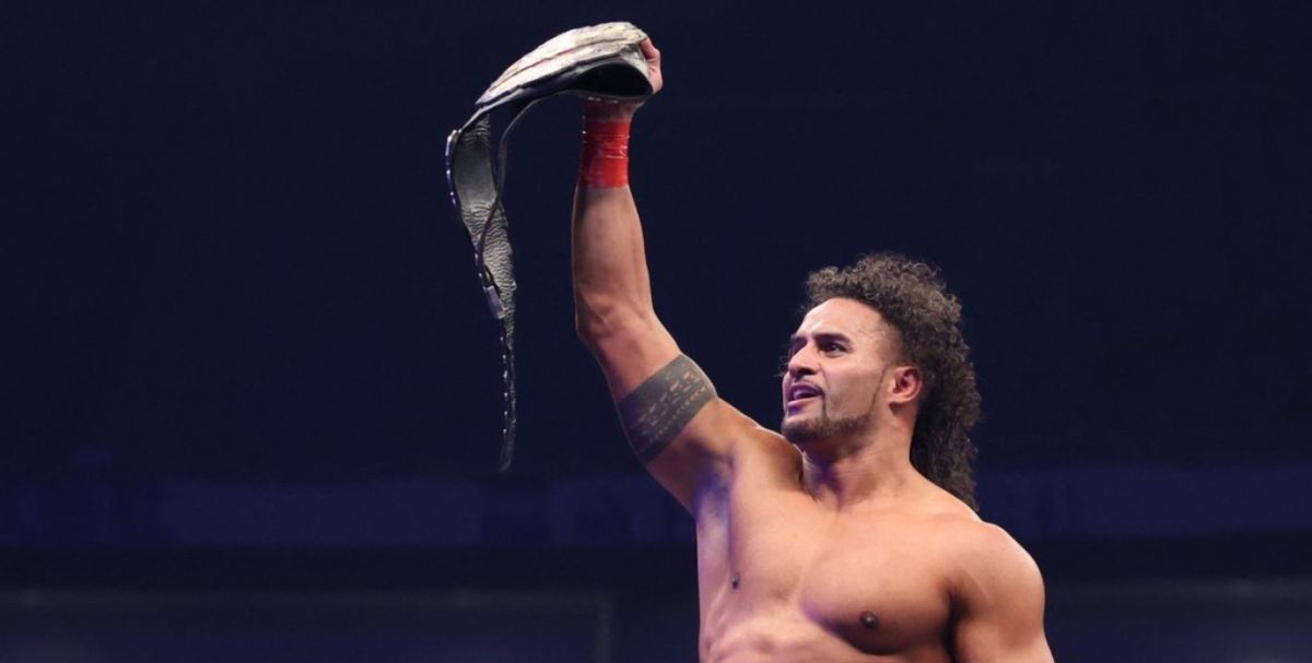 Tama Tonga holds up championship gold under the NJPW banner.