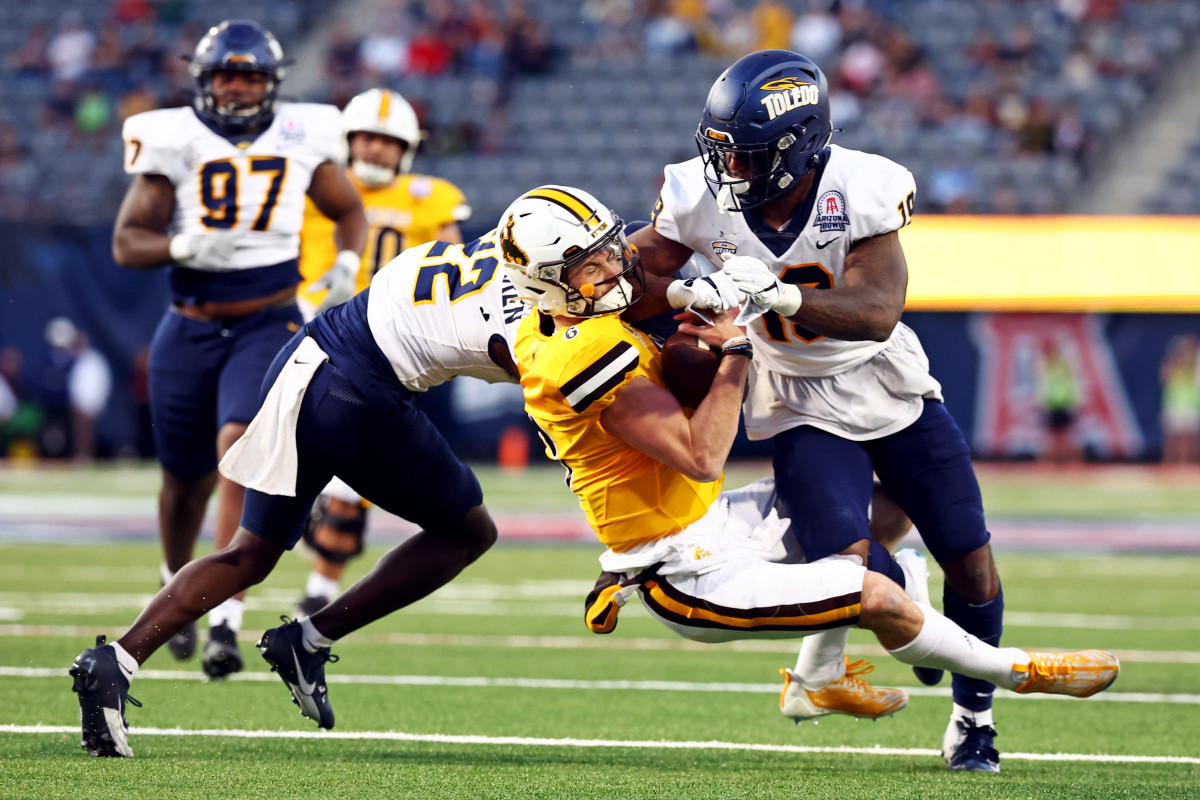 Wyoming Cowboys quarterback Andrew Peasley (6) is hit and tackled by Toledo Rockets linebacker Dallas Gant (19)