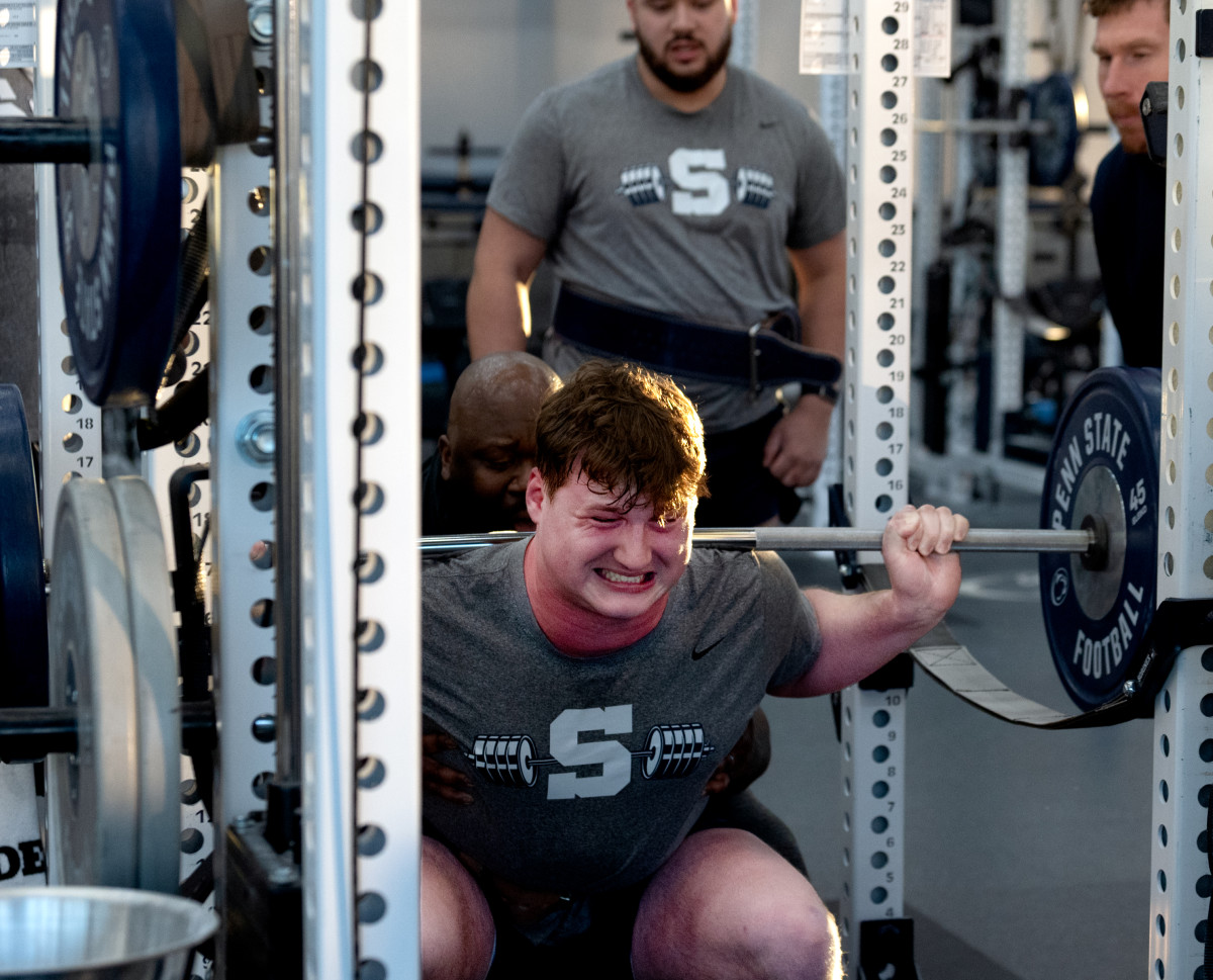 Penn State offensive lineman Alex Birchmeier goes through a lifting drill as position coach Phil Trautwein watches at the Lasch Football Building.