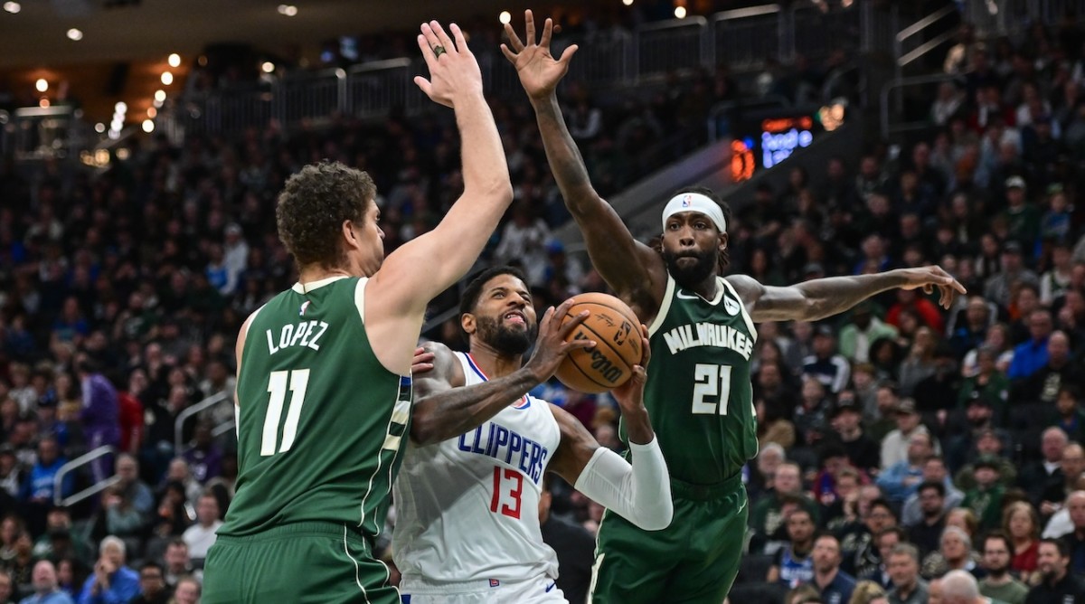 Los Angeles Clippers forward Paul George (13) takes a shot between Milwaukee Bucks center Brook Lopez (11) and guard Patrick Beverley (21) in the second quarter at Fiserv Forum in Milwaukee on March 4, 2024.