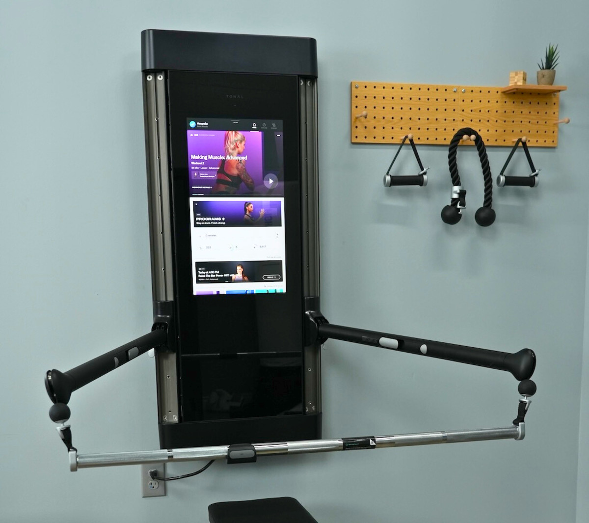 A Tonal home workout system, with touchscreen, adjustable arms and attachments.