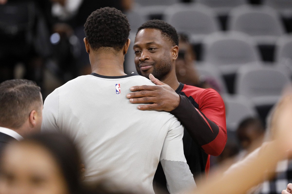 Miami Heat shooting guard Dwyane Wade (behind) hugs San Antonio Spurs shooting guard DeMar DeRozan (front)