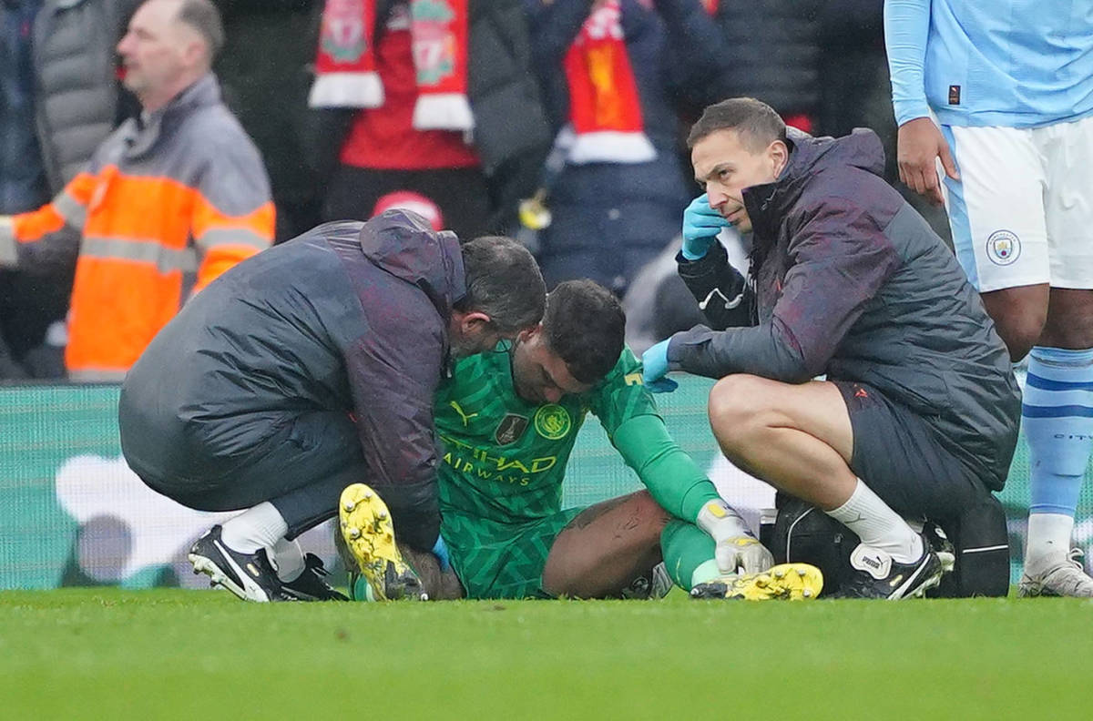 Manchester City goalkeeper Ederson pictured (center) receiving medical treatment during his team's 1-1 draw at Liverpool in March 2024