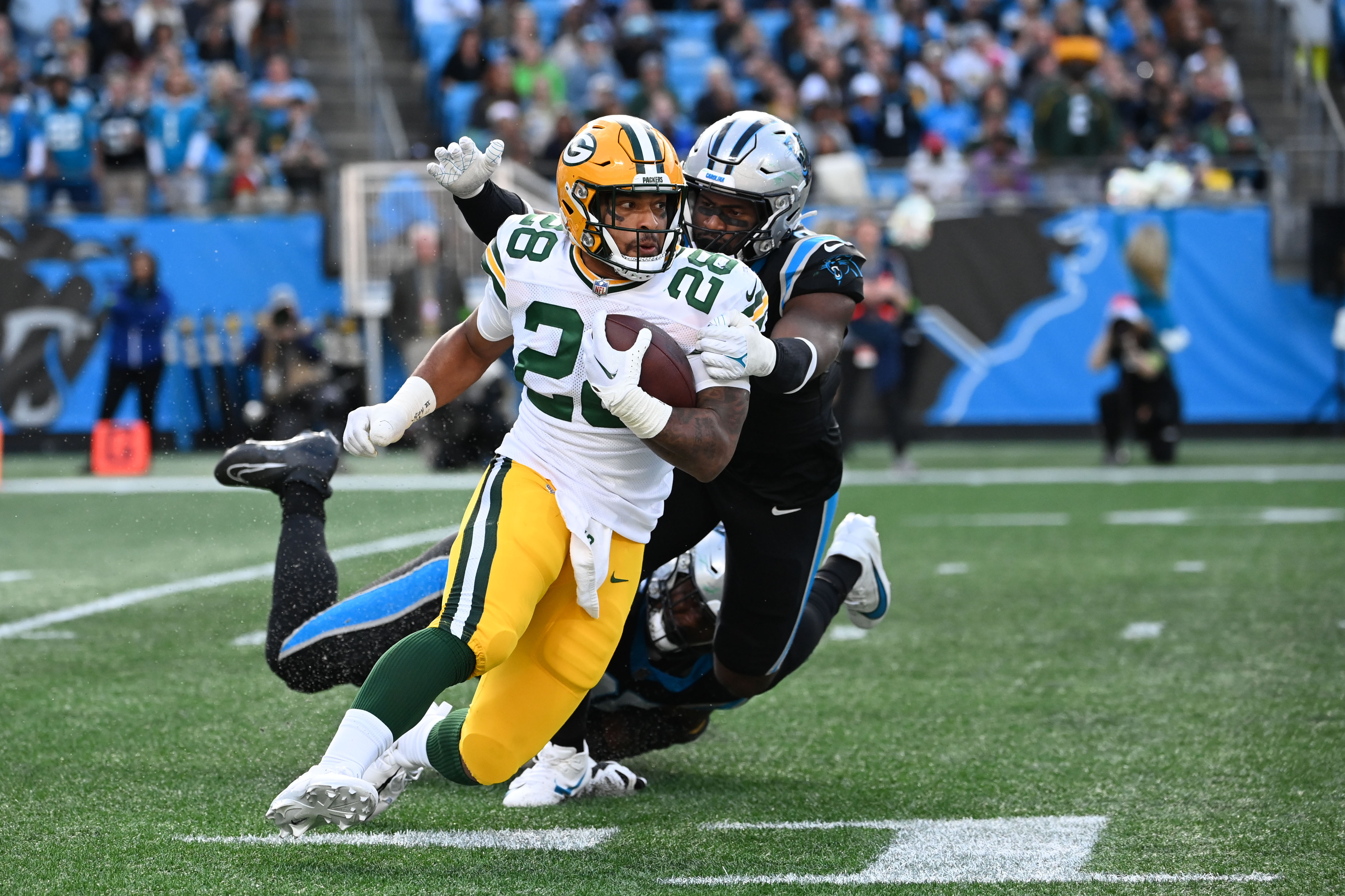 Dec 24, 2023; Charlotte, North Carolina, USA; Green Bay Packers running back AJ Dillon (28) with the ball as Carolina Panthers defensive tackle DeShawn Williams (96) and linebacker Brian Burns (0) defend in the fourth quarter at Bank of America Stadium.