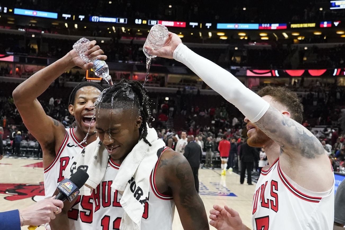 Chicago Bulls guard Ayo Dosunmu (center) is doused with water by forward Dalen Terry (left) and forward Onuralp Bitim (right)