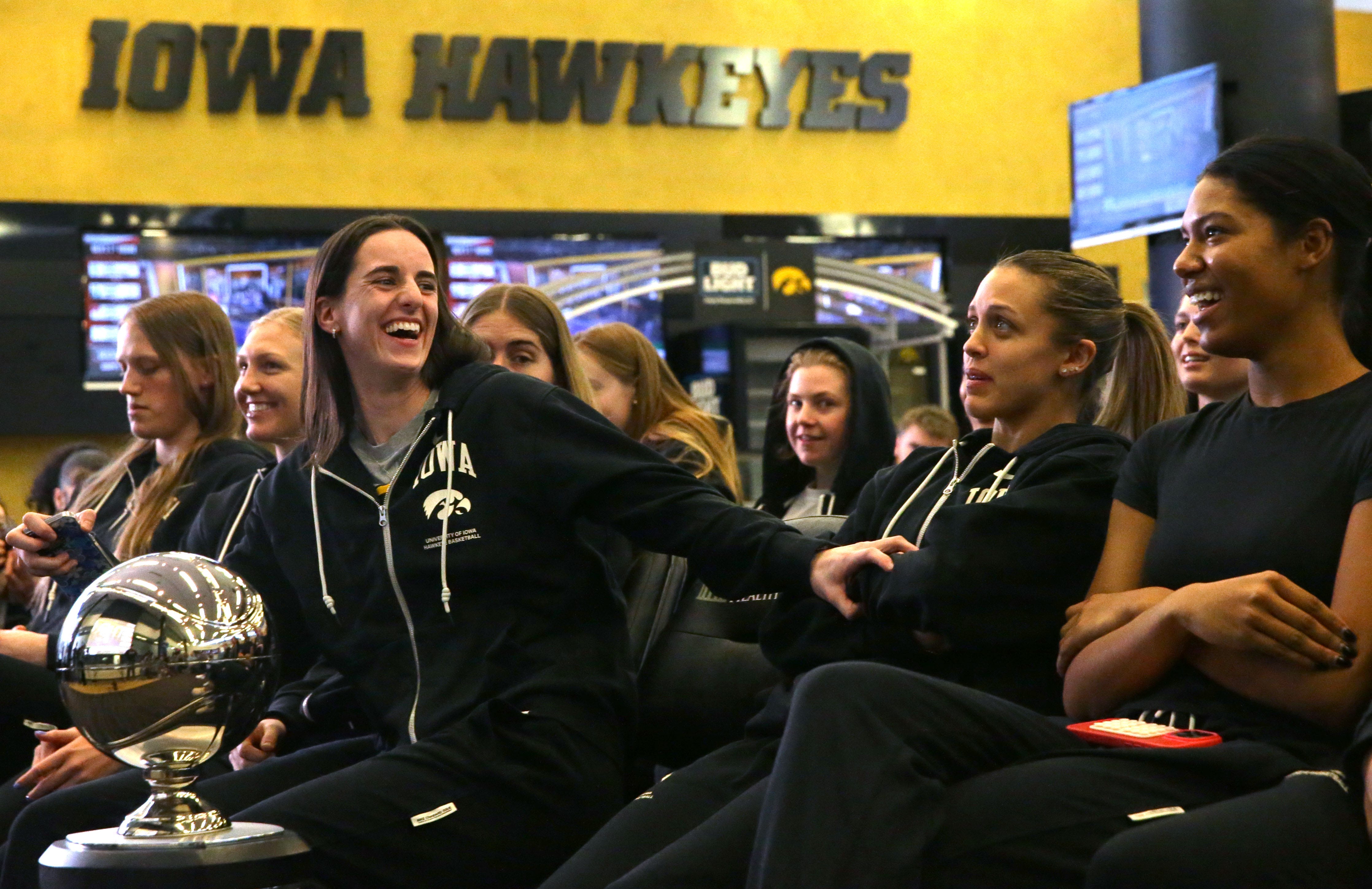 Caitlin Clark smiles with her Iowa teammates while watching the bracket reveal for the NCAA women’s tournament.