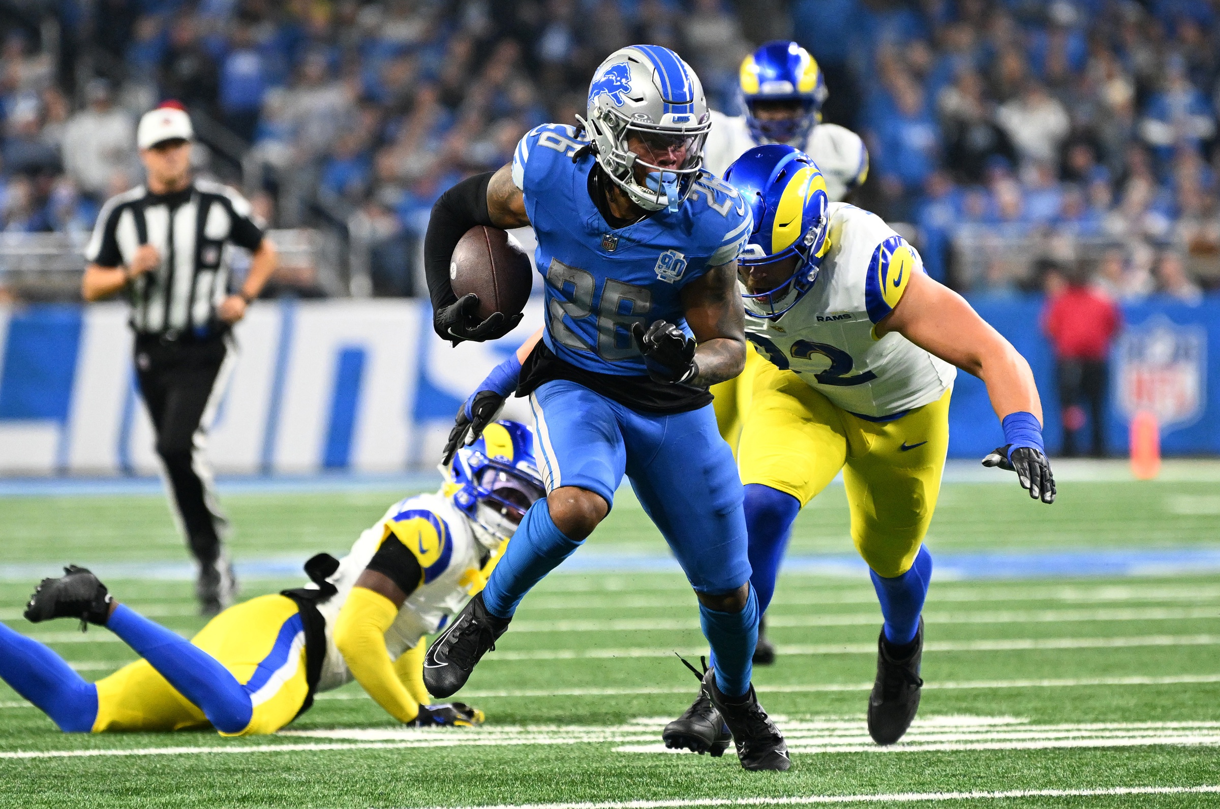 Jan 14, 2024; Detroit, Michigan, USA; Detroit Lions running back Jahmyr Gibbs (26) runs against Los Angeles Rams defensive end Jonah Williams (92) during the first half of a 2024 NFC wild card game at Ford Field.