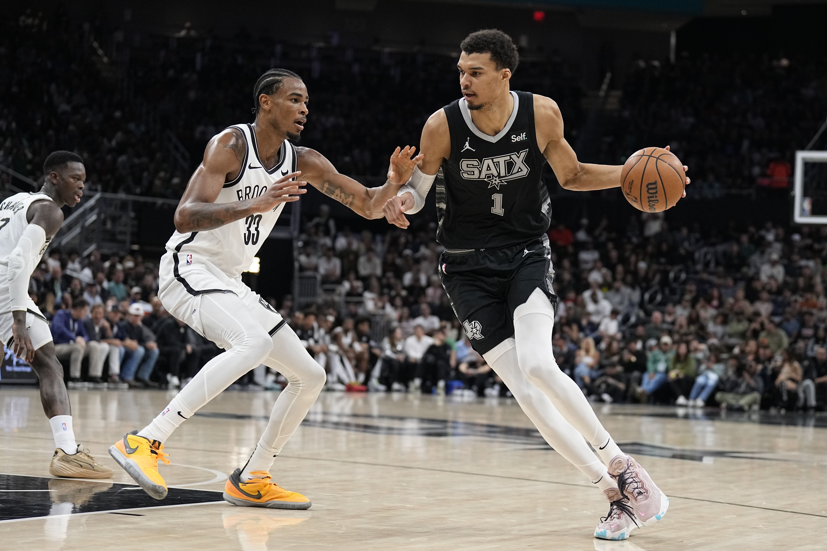 San Antonio Spurs forward Victor Wembanyama (1) drives to the basket while defended by Brooklyn Nets center Nicolas Claxton (33)