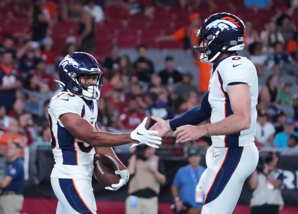 Denver Broncos running back Jaleel McLaughlin (38) slaps hands with Denver Broncos quarterback Ben DiNucci (6) after scoring a touchdown against the Arizona Cardinals during the second half at State Farm Stadium.
