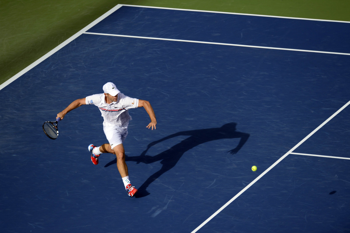 Andy Roddick brings his racket back to prepare to swing at a tennis ball bouncing toward him