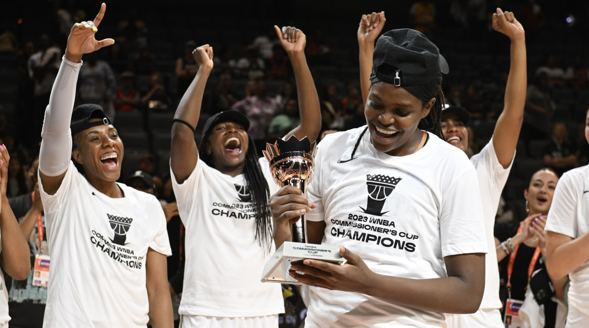 New York Liberty forward Jonquel Jones smiles after being named the MVP of the Commissioner's Cup with teammates cheering behind her.