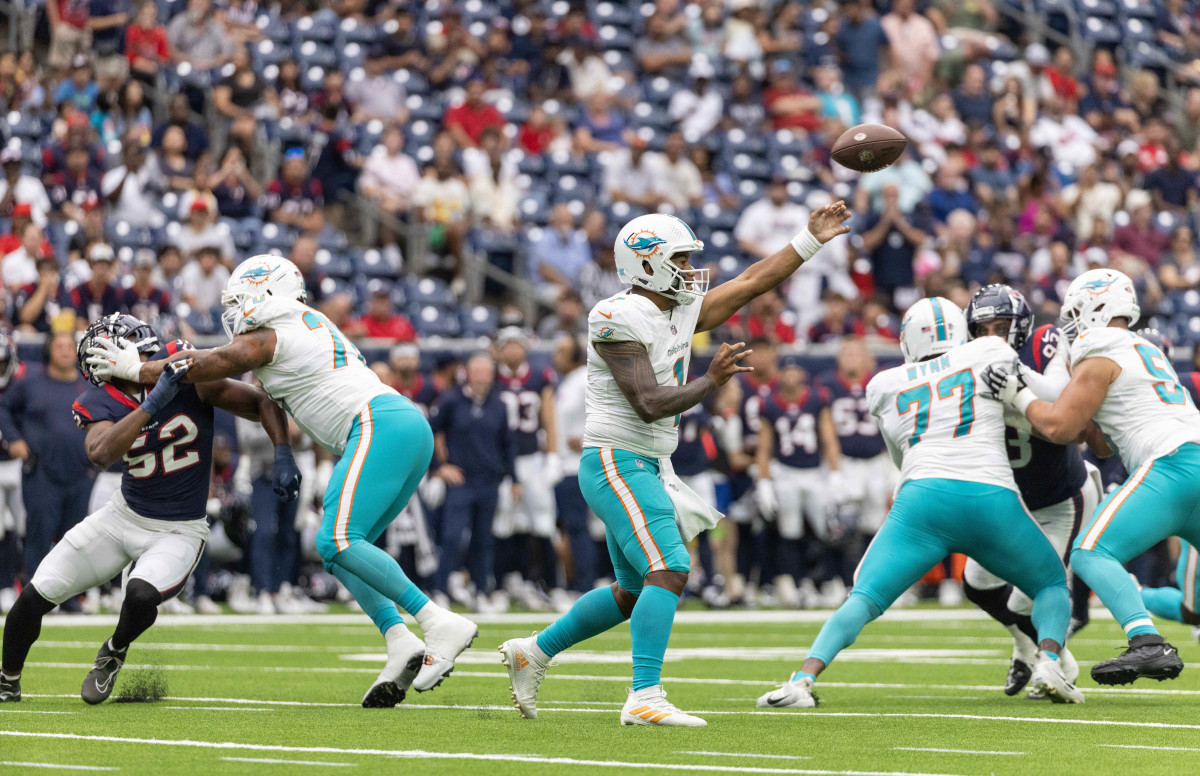 quarterback Tua Tagovailoa throws the ball as Dolphins and Texans players around him attempt to block each other