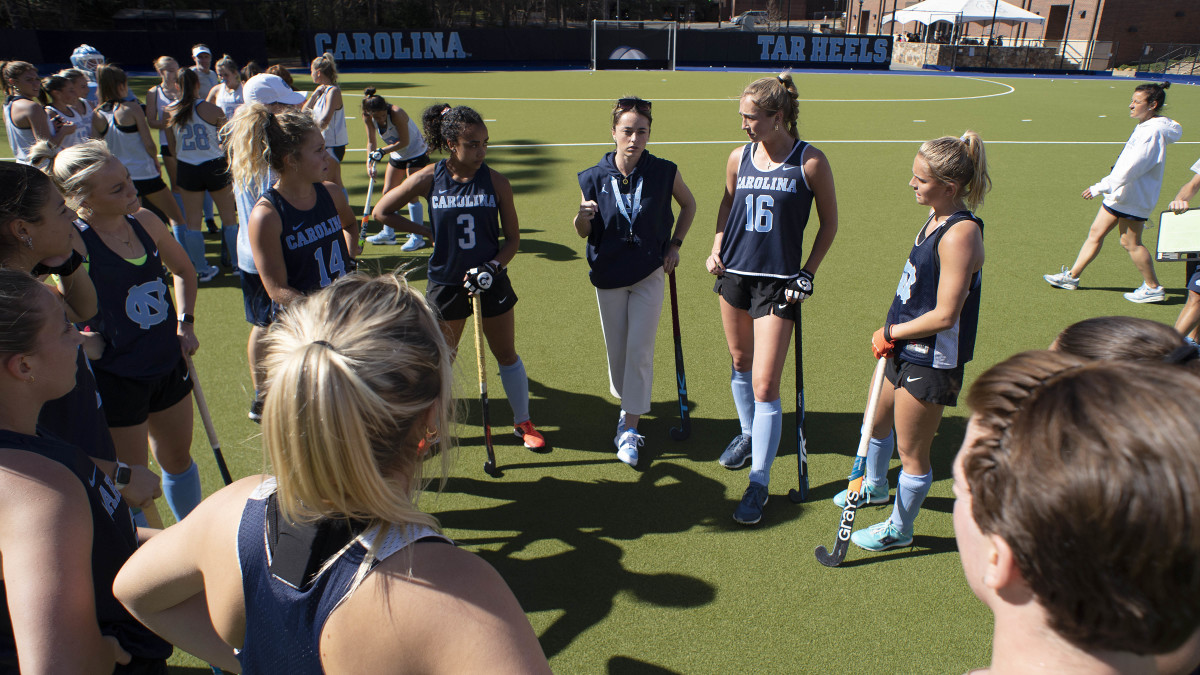 UNC field hockey coach Erin Matson stands in a circle with and speaks to her players at practice.