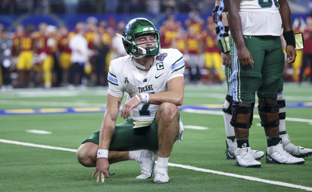 Michael Pratt kneels down on the field with one hand out to balance him, looking toward the sideline
