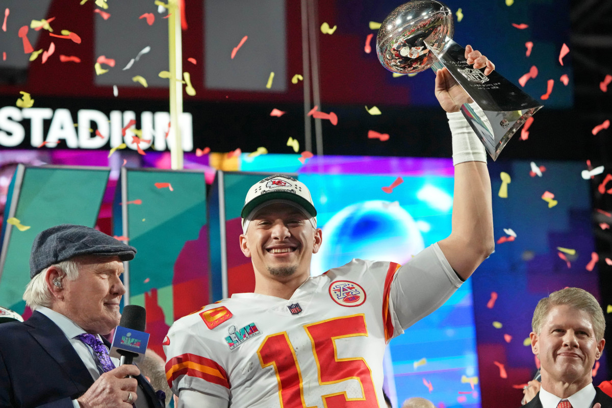 Kansas City Chiefs quarterback Patrick Mahomes lifts the Vince Lombardi Trophy in the air with one hand, smiling after the Super Bowl