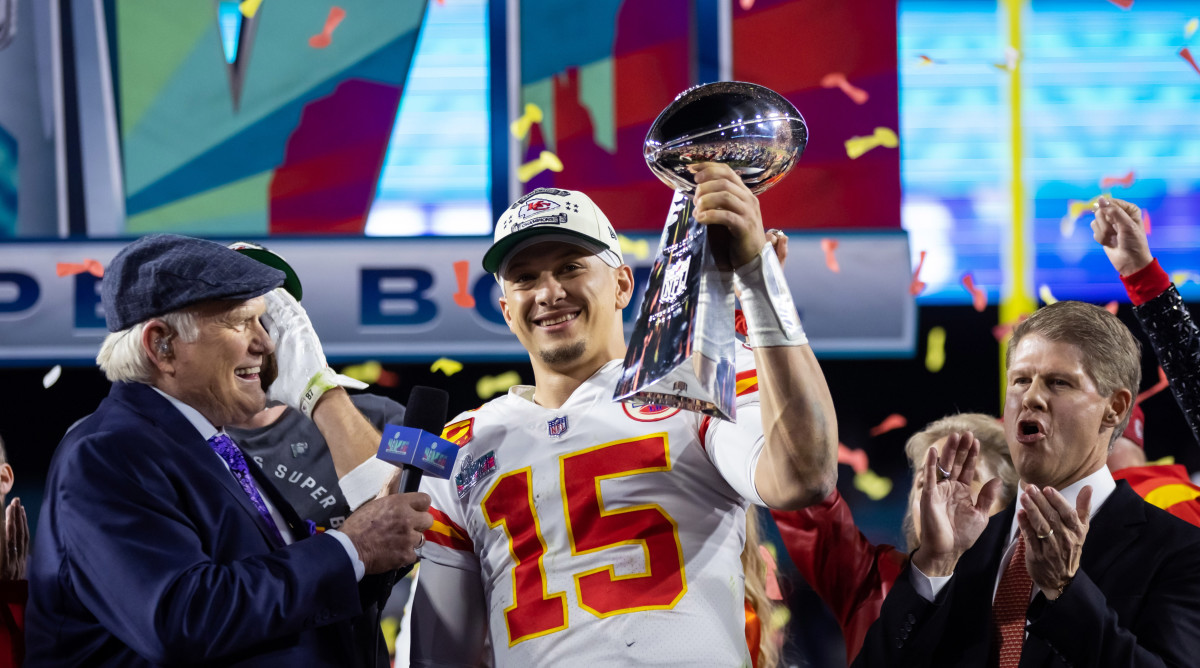Patrick Mahomes holds up the Lombari trophy in one hand as a man holds a mic toward him and confetti falls